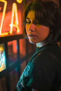 Side view of young woman by illuminated light