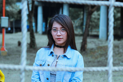 Portrait of young woman seen through rope on land