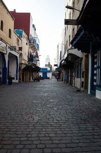 Alley amidst buildings in city against clear sky