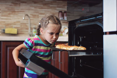 Portrait of smiling young woman holding food in kitchen