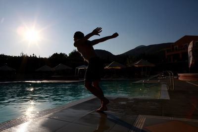 Man diving into swimming pool against sky