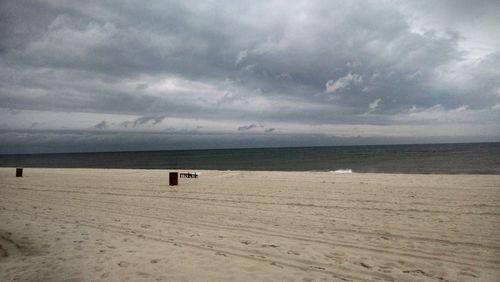 Scenic view of beach against cloudy sky