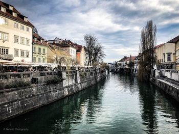 Canal amidst buildings against sky in city