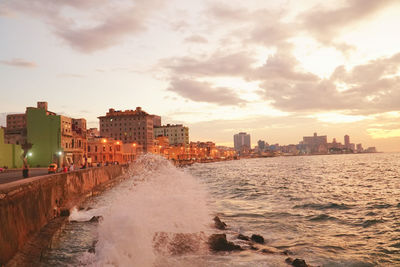 Panoramic view of sea and buildings against sky during sunset