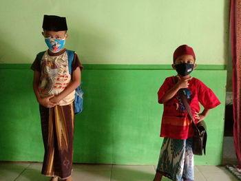 Full length of a boy standing against wall