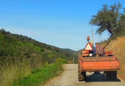 Empty road leading towards mountains against clear blue sky