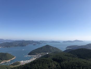 Scenic view of sea and mountains against clear blue sky