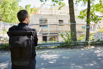 Rear view of architect standing by construction site on sunny day