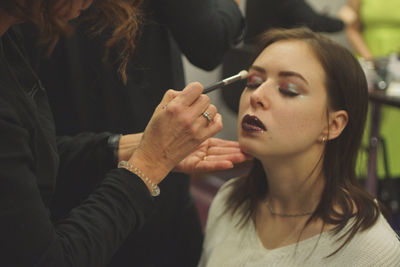 Beautician applying make-up to woman