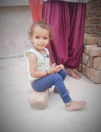 Portrait of a smiling girl sitting on wall