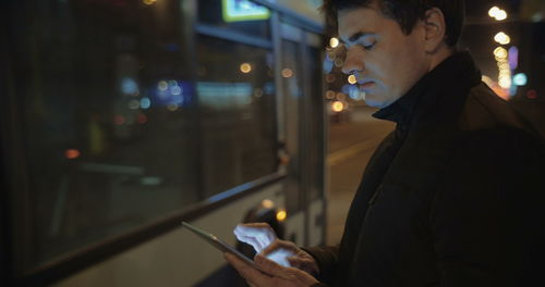Midsection of man using mobile phone at night