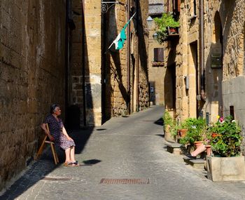 Woman walking on footpath amidst buildings in city