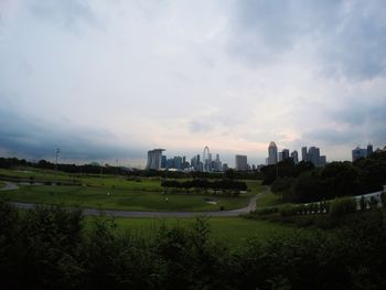 House on grassy field against cloudy sky