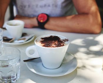 Midsection of coffee cup with cocoa powder on    table 