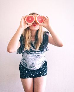 Portrait of beautiful young woman standing against white background