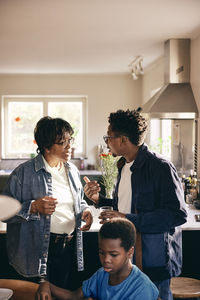 Mature man gesturing while talking to mother while standing at home