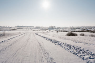 Tire tracks on snow landscape against sky