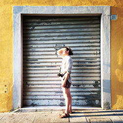 Full length of young woman standing against door