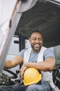 Happy construction worker with hardhat sitting in vehicle