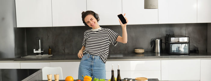 Portrait of young woman standing in kitchen