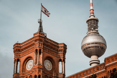 Low angle view of clock tower and fernsehturm against sky