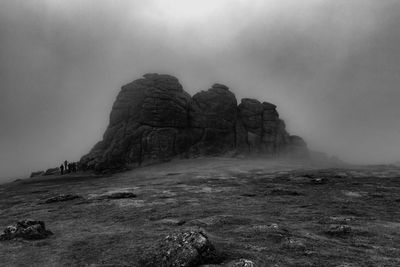 Low angle view of haytor rocks against cloudy sky during foggy weather