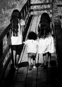 Rear view of children walking on footbridge