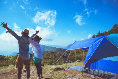 Couple standing on mountain against sky