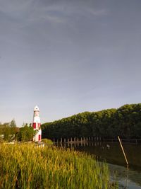 Lighthouse amidst trees and buildings against sky