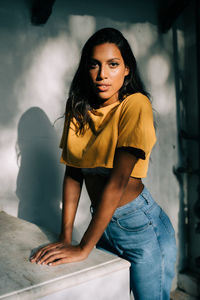 Portrait of young woman standing against wall