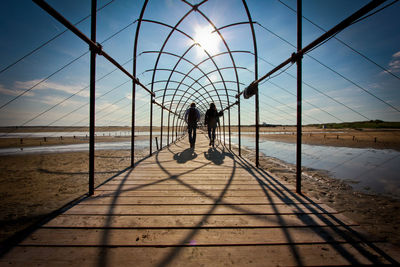 Rear view of man and woman walking on boardwalk