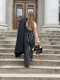 Rear view of woman walking on staircase with graduation cap and gown
