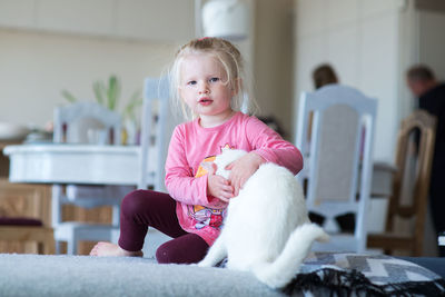Portrait of cute girl sitting with cat at home