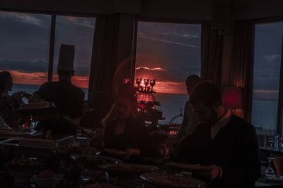 People at restaurant by window during sunset