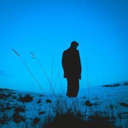Rear view of silhouette man standing by sea against clear blue sky