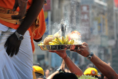 Cropped hands of man holding religious offerings in temple