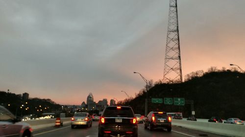 Cars on road in city against sky at dusk