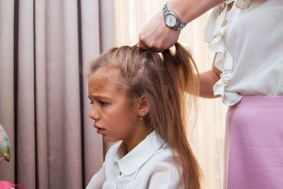 Midsection of mother tying daughter hair