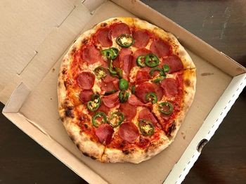 Pizza with pepperoni and jalapeños inside a cardboard box