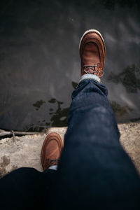 Low section of person wearing shoes by water. person is taking a daring step towards the water. 