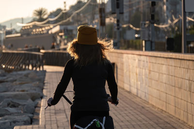 Rear view of woman cycling on footpath