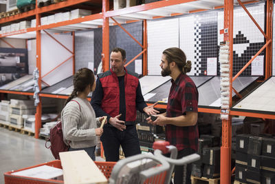 Salesman discussing with couple by shelves at hardware store