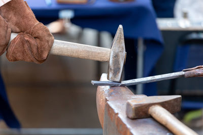 Cropped hand of blacksmith working at industry