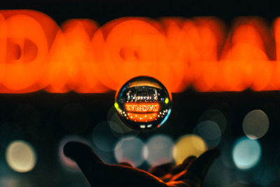 Close-up of hand holding illuminated text at night