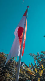 Low angle view of flags against clear blue sky