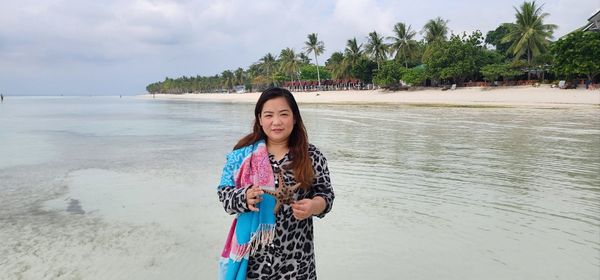 Portrait of young woman standing at beach