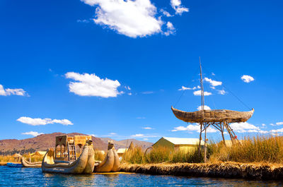 Ship moored in lake against cloudy sky