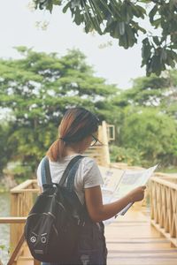 Side view of woman standing against trees