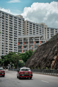 Cars on road by buildings against sky in city