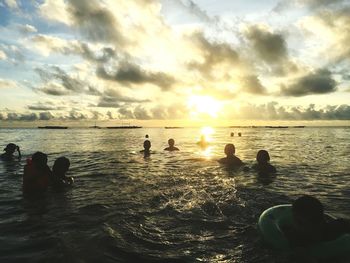 Silhouette people at beach against sky during sunset